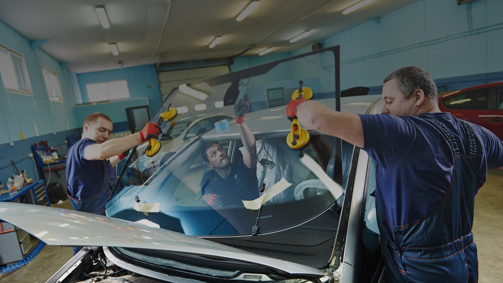 Technicians fitting a windscreen to a vehicle